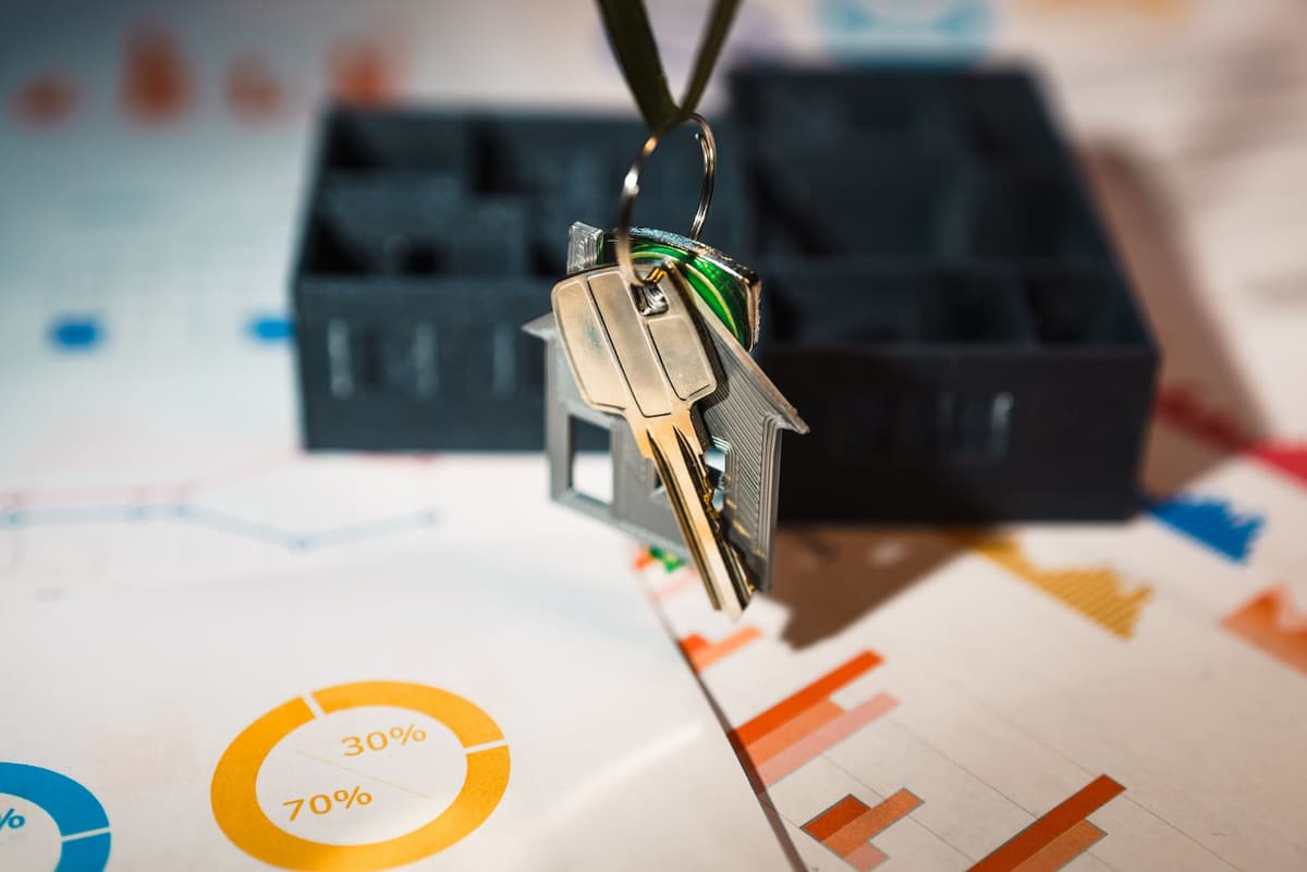 House-shaped keyring and keys hanging above printed pie charts showing percentage splits